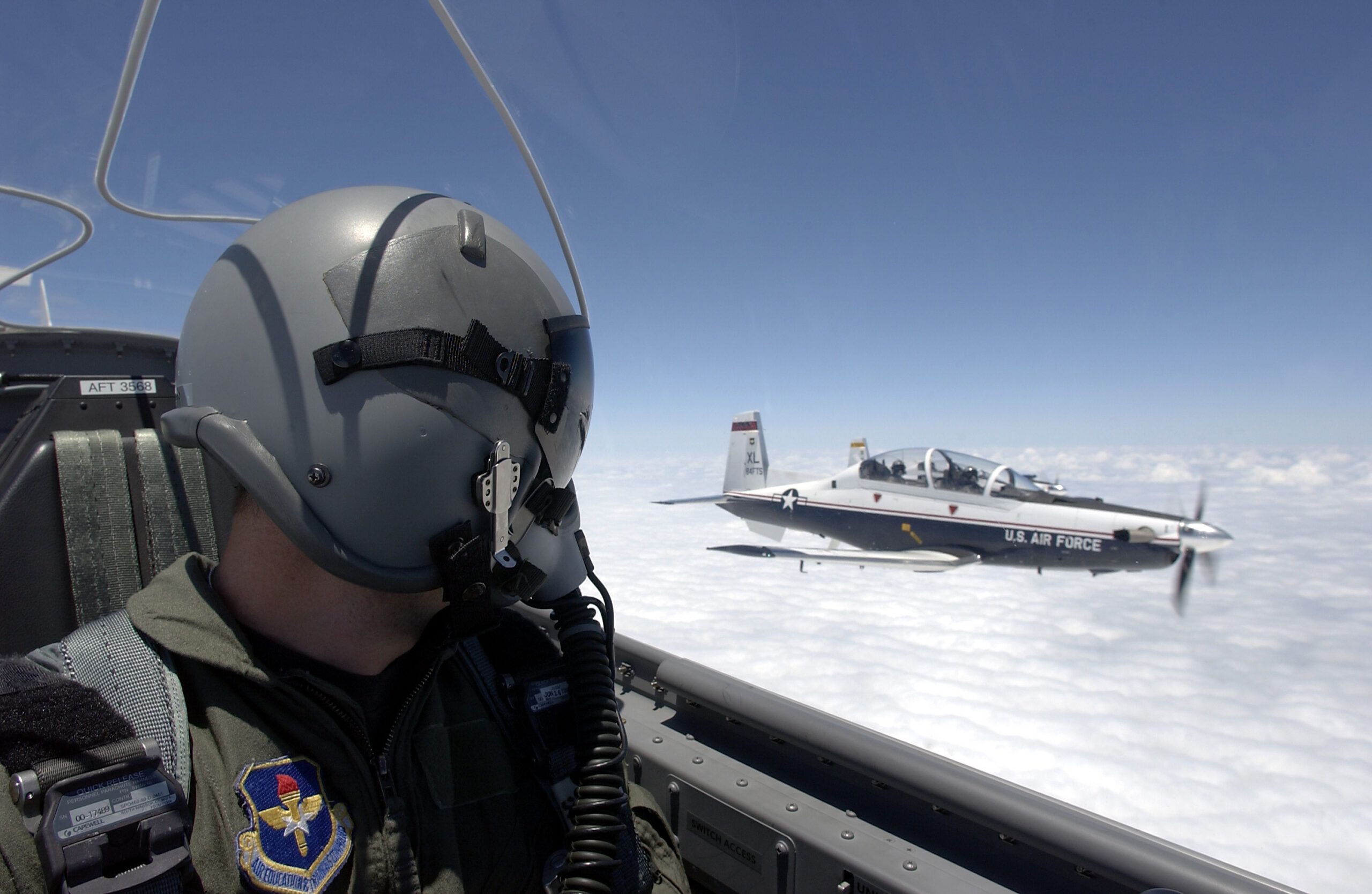 Texans over Texas Air Force Pilot in helmet and oxygen mask looks from his plane to a plane just off of his left wing.