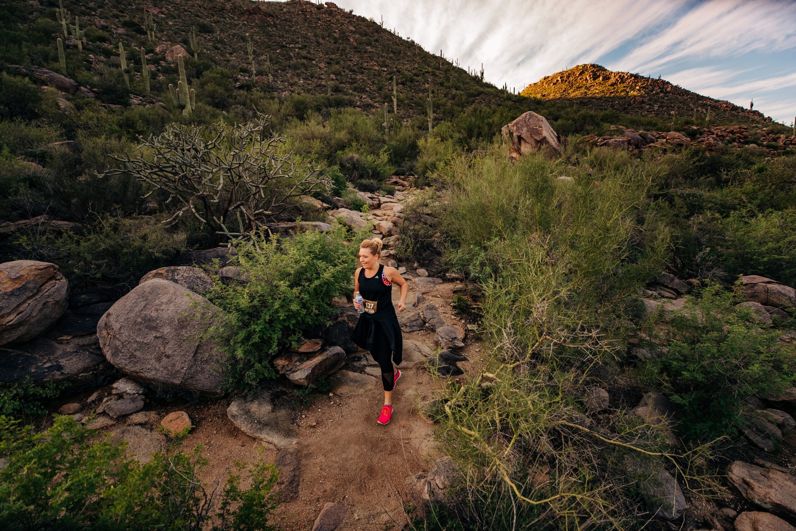Female in black running suit running through a desert trail
