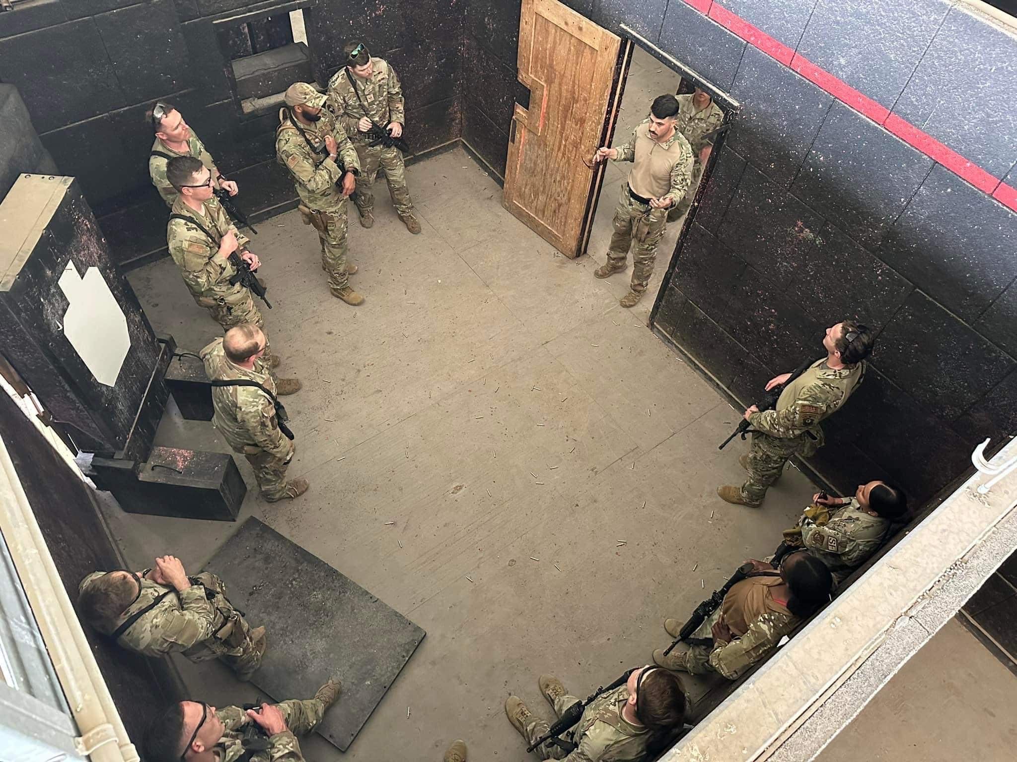 A group of military men gathered in a live fire shoot house conducting training in close quarters battle