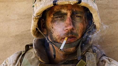 military member in full battle gear, smoking a cigarette. his stare is distant and unfocused, "the thousand yard stare"