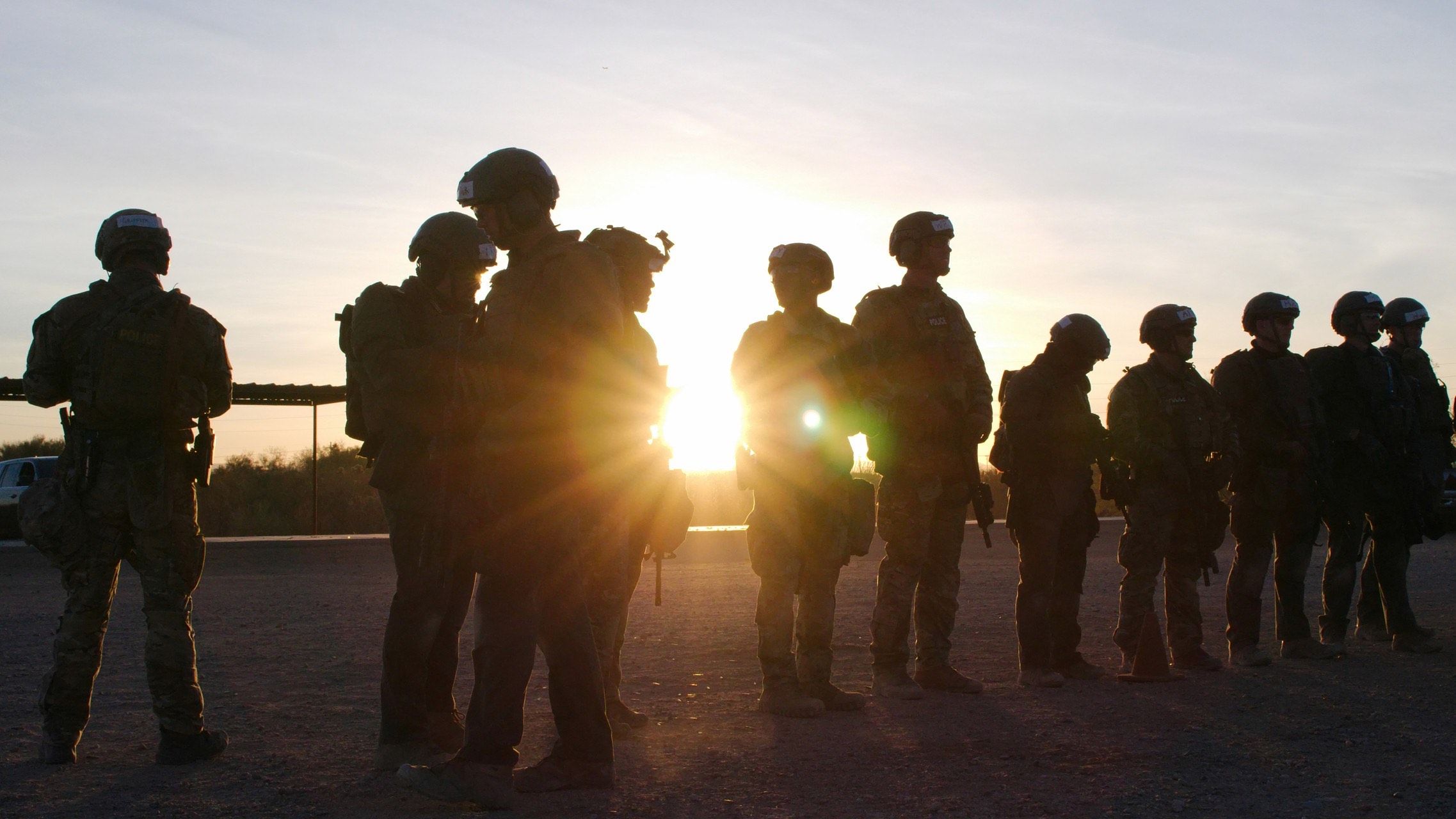 A tactical team, with full gear on in the sunrise on the range for some training